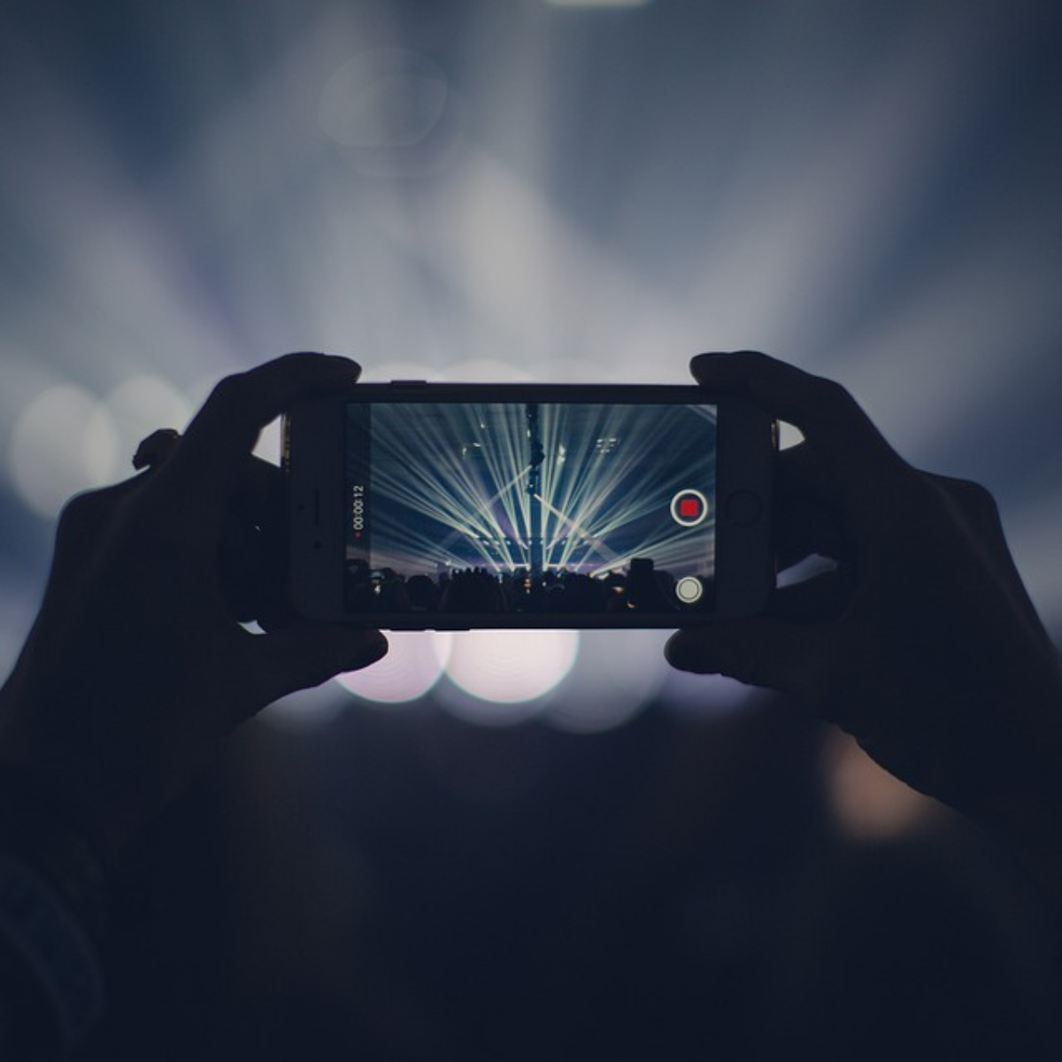 Video-Content auf Facebook. Auf dem Bild ist ein Handy zu sehen, welches auf einem Konzert eine Videoaufnahme macht.